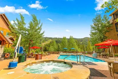 a large swimming pool in a yard with umbrellas at 1 Bedroom Silvermill Rental In River Run Village Steps From The River Run Gondola in Dillon