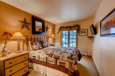a bedroom with a bed and a dresser and a window at 2 Bedroom Colorado Vacation Rental In River Run Village With Pool And Hot Tub Access in Keystone