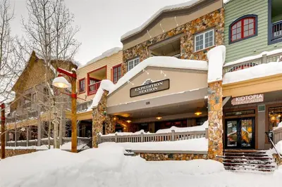 a snow covered street in front of a building at 2 Bedroom Colorado Vacation Rental In River Run Village With Pool And Hot Tub Access in Keystone