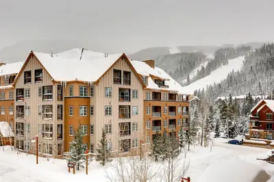 a large apartment building in the snow with snow at 2 Bedroom Colorado Vacation Rental In River Run Village With Pool And Hot Tub Access in Keystone