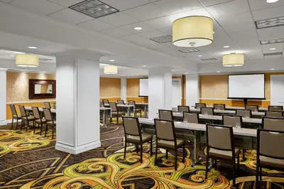 a conference room with tables and chairs and a screen at Kimpton Hotel Monaco Denver by IHG in Denver