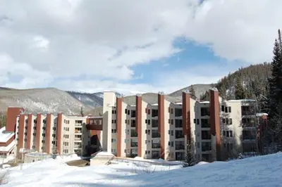 a large building in the snow with mountains in the background at Iron Horse Building D Unit 4104 in Winter Park