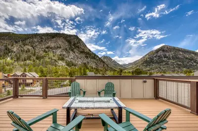 a deck with a table and chairs and mountains at 2nd Ave Luxury in Frisco