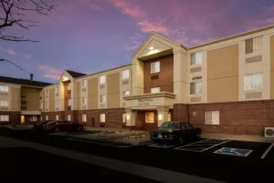 a building with two cars parked in a parking lot at MainStay Suites Denver Tech Center in Centennial