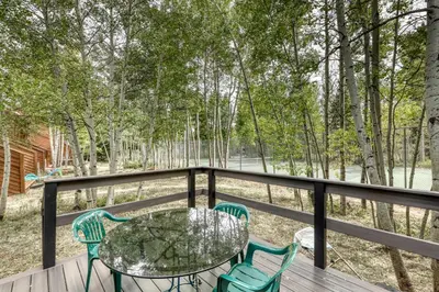 a table and chairs on a deck with trees at Alpine Abode in Frisco