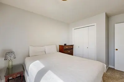 a bedroom with a white bed and a wooden dresser at Alpine Abode in Frisco