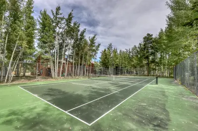 a tennis court with trees in the background at Alpine Abode in Frisco