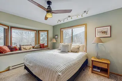 a bedroom with a bed with a ceiling fan and windows at Rivercrest 1 in Frisco