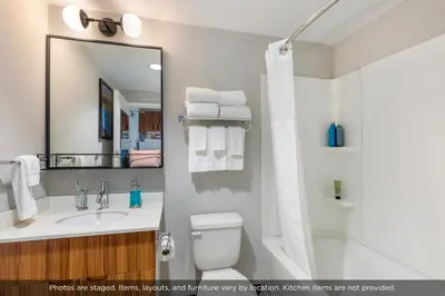 a bathroom with a toilet and a sink and a mirror at Uptown Suites Extended Stay Denver CO -Westminster in Westminster