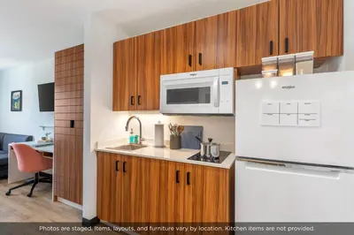 a kitchen with wooden cabinets and a white refrigerator at Uptown Suites Extended Stay Denver CO -Westminster in Westminster