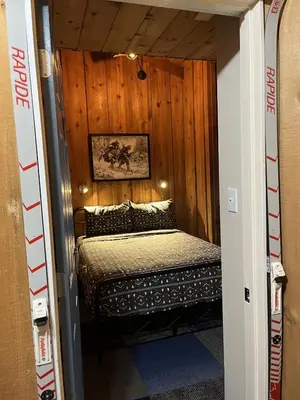 a small bed in a room with a wooden wall at The Viking Lodge - Downtown Winter Park Colorado in Winter Park