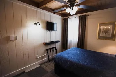 a bedroom with a blue bed and a ceiling fan at The Viking Lodge - Downtown Winter Park Colorado in Winter Park