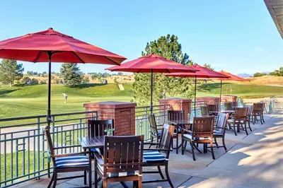 a row of tables and chairs with red umbrellas at Omni Interlocken Hotel in Broomfield