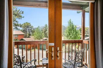 a door to a balcony with two chairs on a porch at Elk Haven in Estes Park