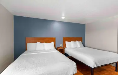 two beds in a room with a blue wall at Extended Stay America Suites - Denver - Airport in Aurora