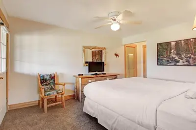 a bedroom with a bed and a desk with a television at Ptarmigan Mountain 202 Condo in Estes Park