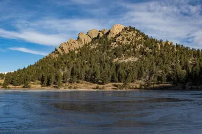 a mountain with trees in front of a body of water at Ptarmigan Mountain 202 Condo in Estes Park