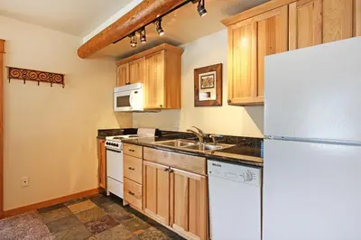 a kitchen with wooden cabinets and a white refrigerator at Little Matterhorn 17A Condo in Estes Park