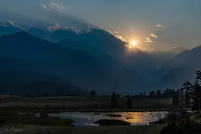 a sunset in the mountains with a river at Powell Peak 104 Condo in Estes Park