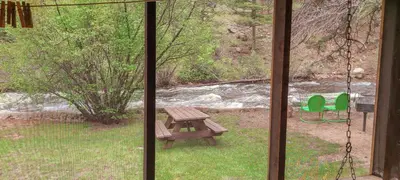 a view of a picnic table and a bench from a window at Idlewilde by the River in Estes Park