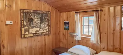 a bedroom with a wooden wall with a picture on the wall at Idlewilde by the River in Estes Park