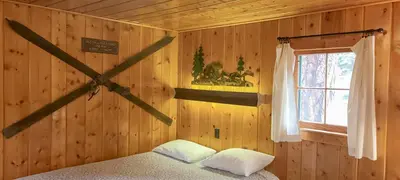 a bedroom with a wooden wall with a bed and a window at Idlewilde by the River in Estes Park
