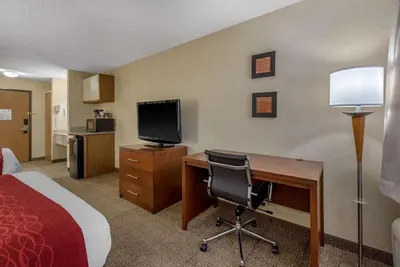 a hotel room with a desk with a computer and a bed at Comfort Inn Denver Southeast Area in Aurora