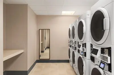 a laundry room with three washing machines and a mirror at Residence Inn Denver Cherry Creek in Denver