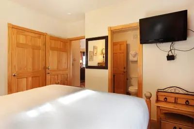 a bedroom with a white bed and a flat screen tv at Chiefs Head Peak 21B Condo in Estes Park