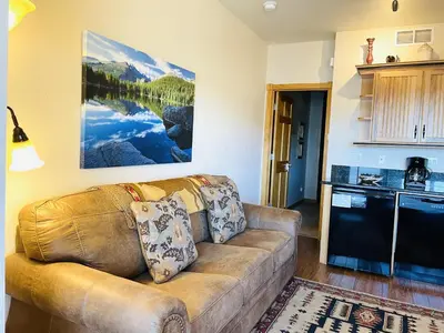 a living room with a couch and a kitchen at Horsetooth Peak 26C Condo in Estes Park