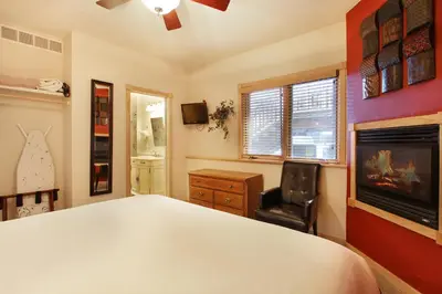 a bedroom with a bed and a chair and a fireplace at Lookout Mountain 27B Condo in Estes Park
