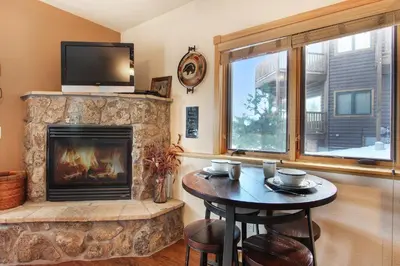 a living room with a fireplace and a table with chairs at Lookout Mountain 27B Condo in Estes Park