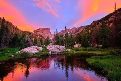 a sunset over a river with a mountain in the background at Snowdrift Peak 203 Condo in Estes Park