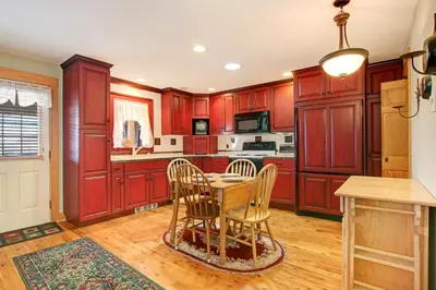 a kitchen with red cabinets and a table and chairs at Snowdrift Peak 203 Condo in Estes Park