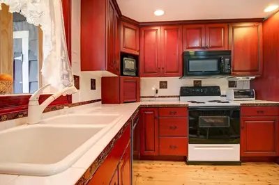 a kitchen with red cabinets and a sink and a stove at Snowdrift Peak 203 Condo in Estes Park