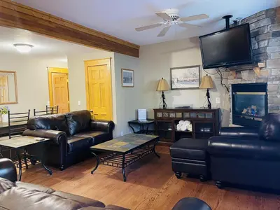a living room with leather furniture and a stone fireplace at Hallett Peak 101 Condo in Estes Park