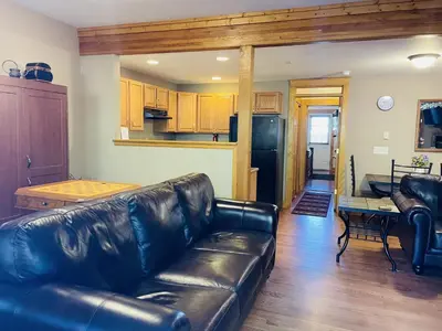 a living room with a leather couch and a kitchen at Hallett Peak 101 Condo in Estes Park
