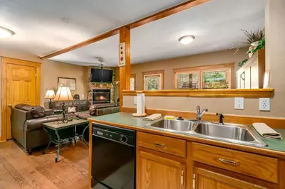 a kitchen with a sink and a living room at Hallett Peak 101 Condo in Estes Park