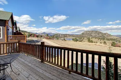 a wooden deck with a view of a lake and mountains at Nisa Mountain 36 Condo in Estes Park