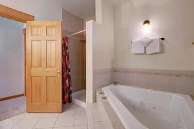 a bathroom with a tub and a shower and a door at Nisa Mountain 36 Condo in Estes Park