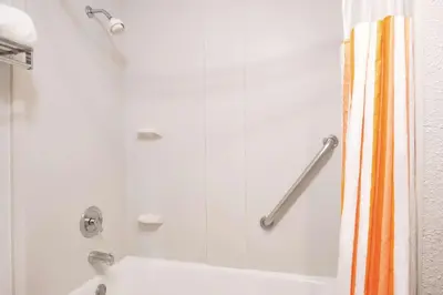 a shower with an orange shower curtain in a bathroom at Mountain Valley Inn & Suites in Silverthorne