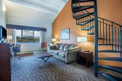 a living room with a spiral staircase and a couch at Mountain Valley Inn & Suites in Silverthorne