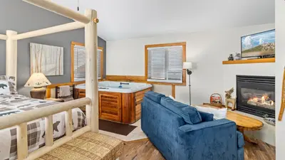 a bedroom with a blue couch and a bed and a fireplace at Mountain Shadows Resort in Estes Park