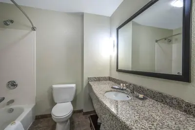 a bathroom with a toilet and a sink and a mirror at La Quinta Inn & Suites by Wyndham Loveland Estes Park in Loveland