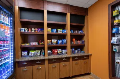 a pantry with wooden cabinets and shelves with food at La Quinta by Wyndham Denver Southwest Lakewood in Lakewood