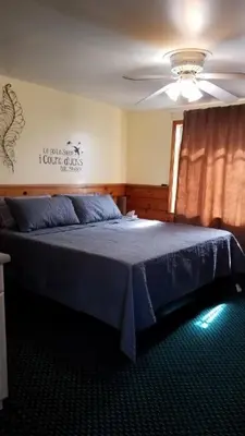 a bedroom with a blue bed with a ceiling fan at Stone Mountain Lodge in Lyons