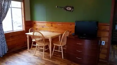 a dining room with a table and chairs and a television at Stone Mountain Lodge in Lyons