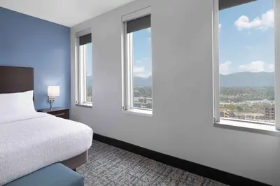 a bedroom with a bed and windows with a view at Homewood Suites- Denver Downtown Convention Center in Denver