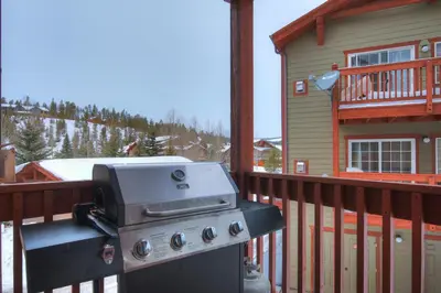 a grill sitting on a deck next to a house at Swans Nest Villa 1601 Condo in Breckenridge