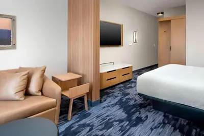 a hotel room with a bed and a couch and a tv at Fairfield Inn & Suites by Marriott Denver Tech Center North in Denver